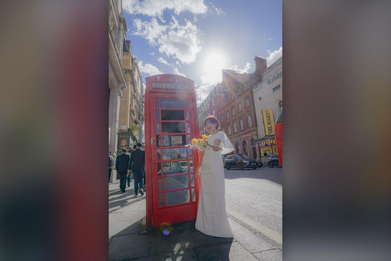 ロンドンの赤い電話ボックスの前に立つ花嫁